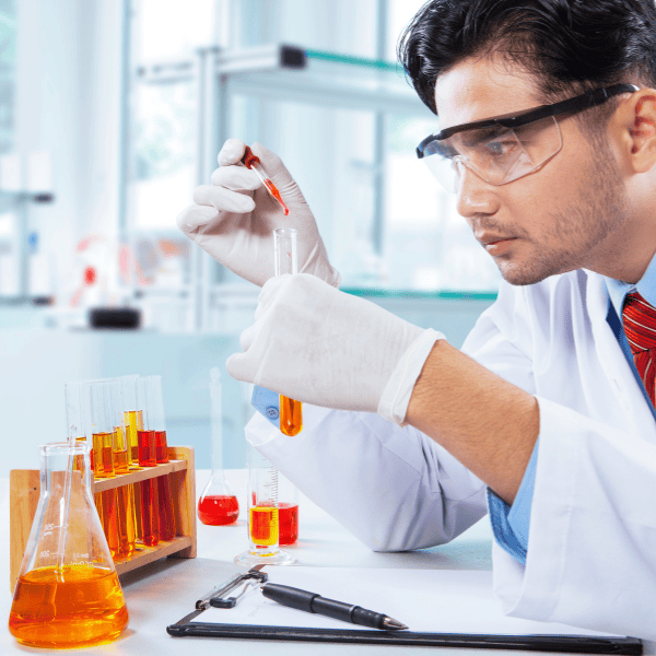 Scientist wearing lab coat and gloves holding beaker and taking notes