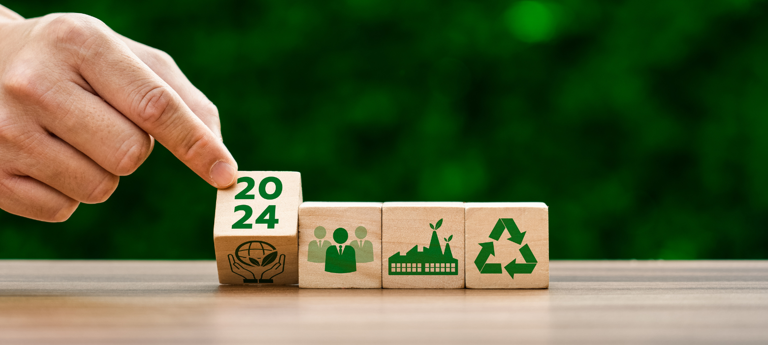 four wood blocks with 2024, business professionals, a factory, and a recycle symbol on them