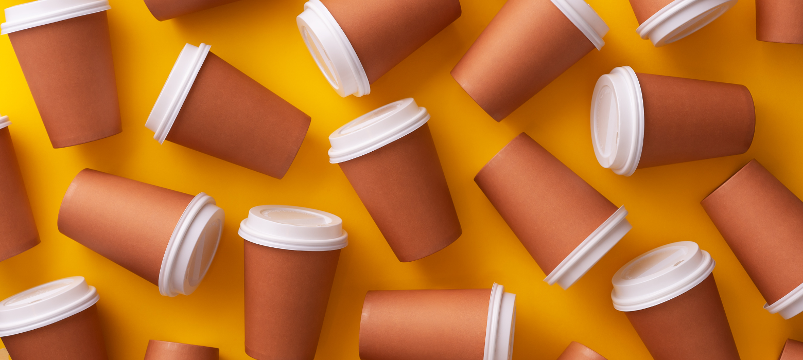 Brown coffee cups with white lids on orange background