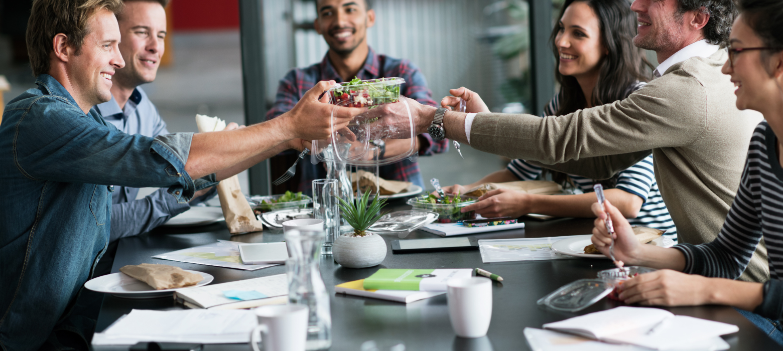 Employees eating lunch at conference room table demonstrating food waste at the office