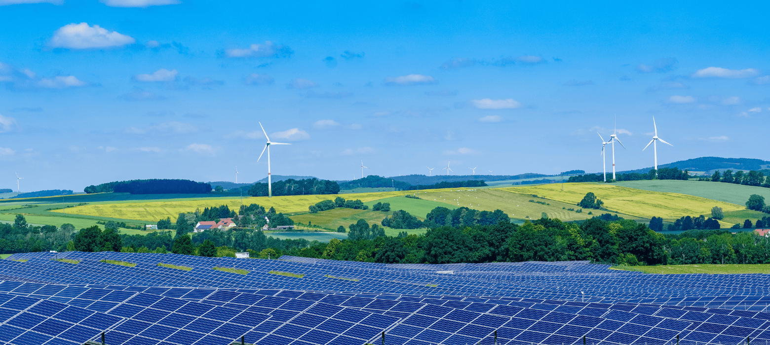 solar panels in a field with wind turbines in the background creating renewable energy