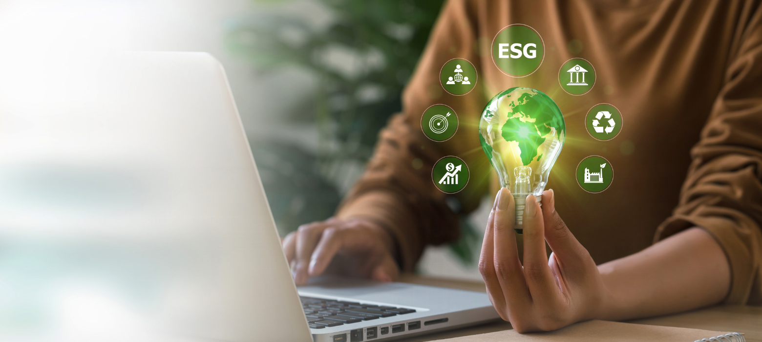 Business professional looking at laptop holding lightbulb showing ESG icons