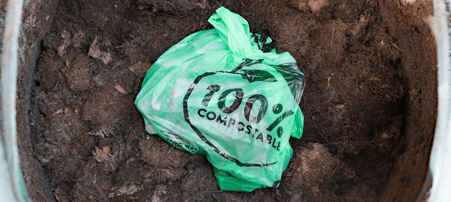 Green compostable bag on pile of composted soil